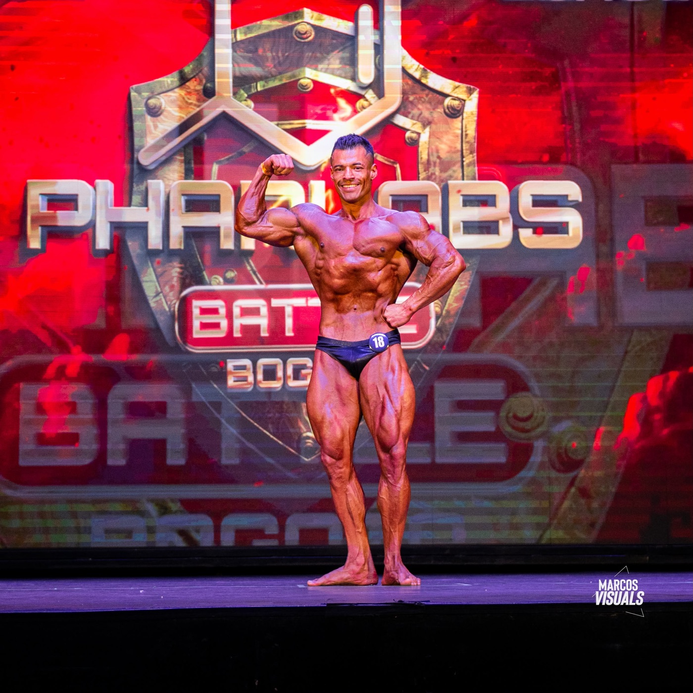 Gio Melchor hitting a front double-biceps pose on stage